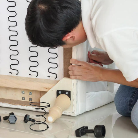 Person repairing a couch with Heavy Duty Six Inch Sofa Spring Repair Kit, ensuring solid support for furniture restoration.