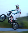 Adult Electric Dirt Bike Built To Shred With Raw Torque And 53 MPH Top Speed performing a wheelie on dirt track.