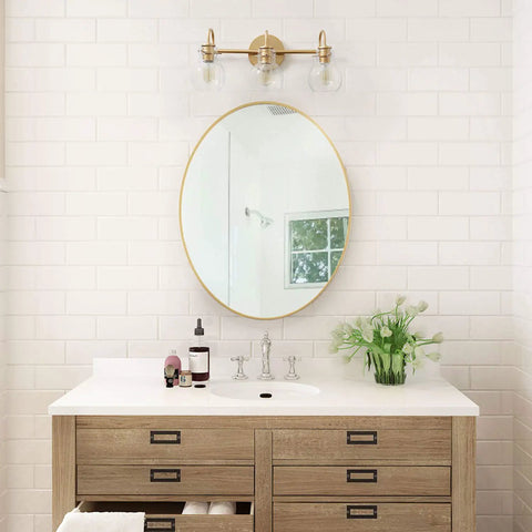 Bathroom with Gold 3 Light Vanity Light Fixture Over Mirror With Globe Clear Glass Shades above a wooden vanity.
