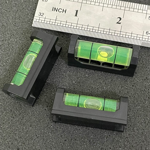 2Pack Magnetic Bubble Levels With Heavy Duty Iron Grip Solid Acrylic Spirit Level on a dark surface with ruler measuring size.