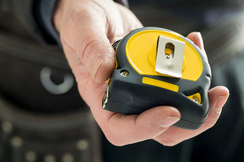 Person holding Fatmax Tape Measure with Blade Armor and Dual Scale 8m Length, Mylar Coated Blade, emphasizing compact design.