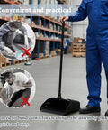 Heavy Duty Upright Standing Dustpan Built Different Tight Pivoting Base used in a warehouse, with ergonomic long handle for ease of use.