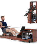 Man using Water Rowing Machine For Home Gym With Foldable Wooden Frame 400 Lb Capacity Quiet Ergonomic Seat Immersive Water Resistance