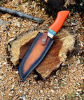 Dope Copper Damascus Fixed Blade Knife With Resin Handle And Premium Leather Sheath resting on wooden stump outdoors.