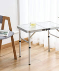 Ultra Portable Folding Camp Table With Aluminum Build 24 Inch Long By 16 Inch Wide Adjustable Height Legs With Two Heights 10 And 19 Inches Lightweight Indoor Outdoor Picnic Table For Camping Tailgating Beach Trips in a living room setting next to a chair.