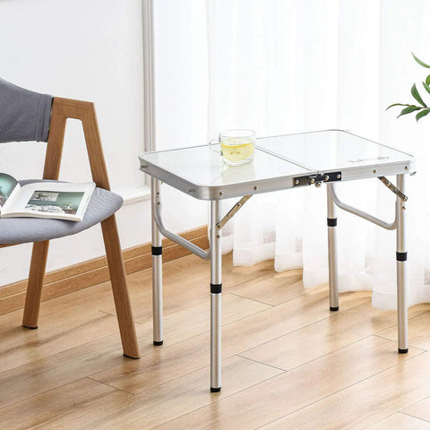 Ultra Portable Folding Camp Table With Aluminum Build 24 Inch Long By 16 Inch Wide Adjustable Height Legs With Two Heights 10 And 19 Inches Lightweight Indoor Outdoor Picnic Table For Camping Tailgating Beach Trips in a living room setting next to a chair.