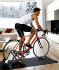 Man using 6 Level Magnetic Bike Trainer With Adjustable Resistance For Indoor Cycling Fits 26-28 Inch And 700C Wheels in living room