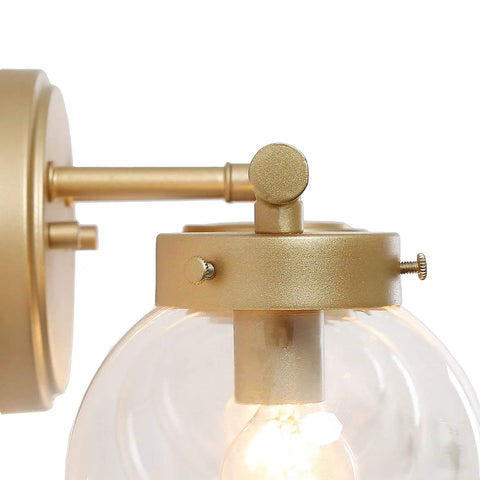Close-up of hand painted vanity light fixtures with clear globe glass shades, clean lined metal arms showcasing unique finish detail.