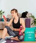 Woman in sportswear with water bottle sitting beside a green Two Pack Large Travel Laundry Bag Waterproof Wet And Dry With Drawstring Closure