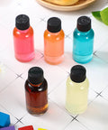 Clear Boston Round Glass Bottles With Black Screw Cap, One Oz Capacity, showing various colorful liquids in a display.