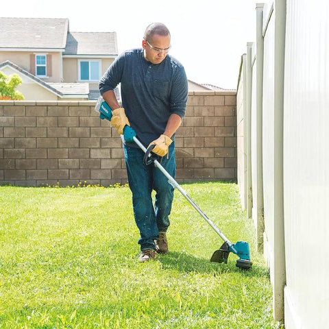 Man using a 13-Inch Cordless String Trimmer With Brushless Motor, 18V LXT, No Gas Emissions, Low Noise Design on grass by fence.