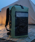 Waterproof Roll-Top Backpack With Padded Straps 35L Daypack For Hiking And Camping, green, next to a tent at dusk