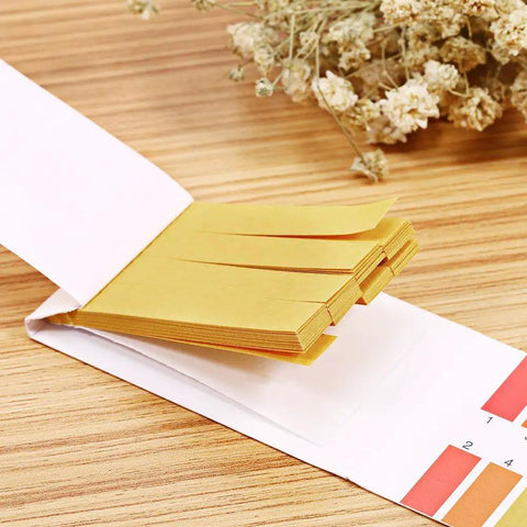 Litmus paper strips from PH Test Strips 0-14, 80 Count Litmus Paper For Saliva Urine Water Soil Testing, shown with color chart.