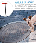 Beefy Steel Manhole Cover Lifter And Roller Shutter Door Hook With A Knuckle Friendly Grip near a manhole cover on pavement.