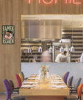 Funny Vintage Ramen Bowl Metal Sign 8x12 Inch Wall Decor in a stylish cafe setting with chefs in the background.