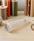 Plastic Yarn Bobbins Set Of 20, Tapered Tower Spools Made From PP Material To Prevent Tangling And Surface Damage, Ideal For Dyeing, Steaming, Bulk Textile Production And Sewing Supplies. White openwork PP yarn bobbin shown on a worktable