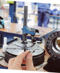 Close-up of hand holding 12 Pack Galvanized Iron Toggle Bolt Wings Drywall Anchors Kit in an industrial workspace