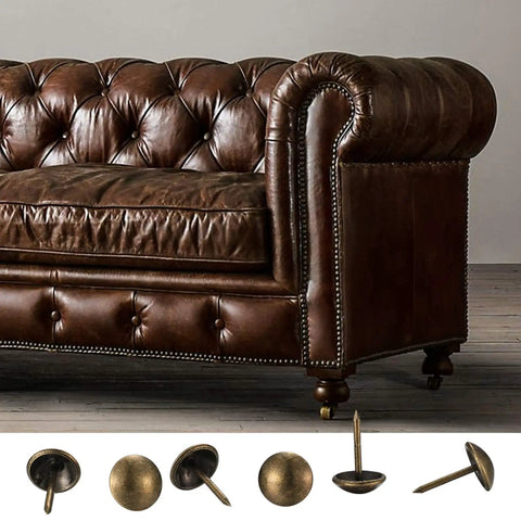 Premium 320 Piece Set Of Top Shelf Upholstery Tacks Featuring A Knockout Antique Brass Finish and Smooth Round Heads displayed with a brown leather sofa.