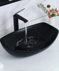 Matte black ceramic vessel sink with running water, featuring minimalist faucet on white countertop, contrasting design elements.