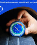 32nds Tire Tread Depth Gauge With Glow In The Dark Luminescent Dial being used on a car tire by a mechanic's hand.