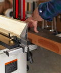 Woodworker using 14-Inch Woodworking Band Saw With 1.75 HP Dual Voltage 115/230V 1Ph Black-Coated Cast Iron Table for cutting wood