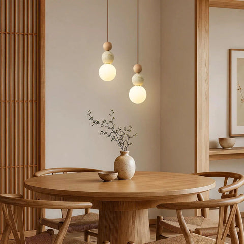 Wabi Sabi Travertine Pendant Light with Wood Ball & Milk Glass Shade hanging over a round wooden table in a cozy dining area.
