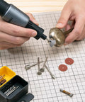 Person using Badass Sixty Piece Rotary Tool Accessory Crate on a metal object, featuring various attachments and tools.