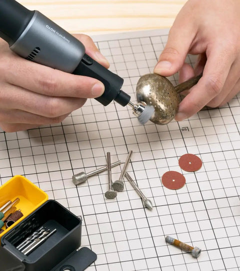 Person using Badass Sixty Piece Rotary Tool Accessory Crate on a metal object, featuring various attachments and tools.
