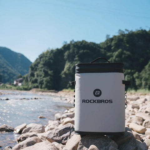 Leakproof Soft Sided Backpack Cooler For 36 Cans, Insulated Waterproof Cooler Bag, Perfect For Camping, Fishing, Picnics, And Outdoor Adventures, Grey, shown by a river with rocky bank.