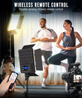 Couple practicing yoga with 2-Pack Pro-Grade Bi-Color LED Photography Lighting Kit, 36W Output, remote in hand, tripod, and camera.