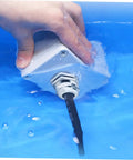Hand testing waterproof feature of 5 Piece Metal Cable Connector Kit with glands in blue water for machinery control boxes.