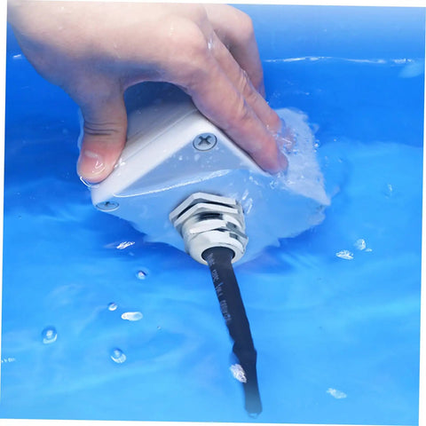 Hand testing waterproof feature of 5 Piece Metal Cable Connector Kit with glands in blue water for machinery control boxes.