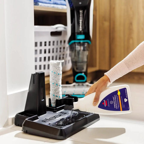 Person pouring FreshStart CrossWave Cleanout Formula 60oz Citrus Scent into CrossWave holder for cleaning and odor prevention.