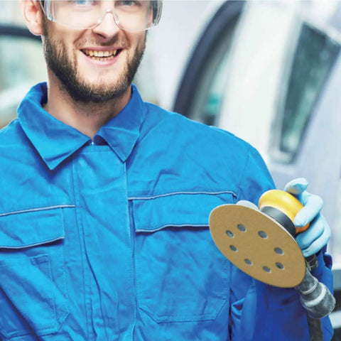 Man in blue overalls holding 5 Inch Hook And Loop Sanding Discs Set 100 Pcs 60 80 120 150 220 Grits Aluminum Oxide