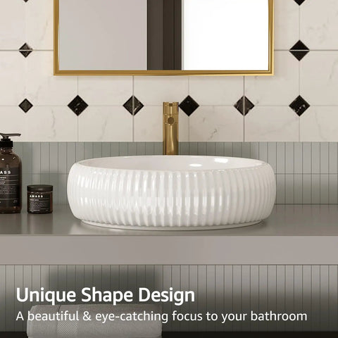 White porcelain vessel sink on a bathroom vanity with textured design, gold faucet, and geometric tile background.