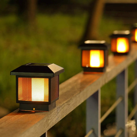 4 Pack Solar Flame Post Lights for Wood Fence Posts illuminating at night, showcasing flickering flame bulbs on wooden posts.