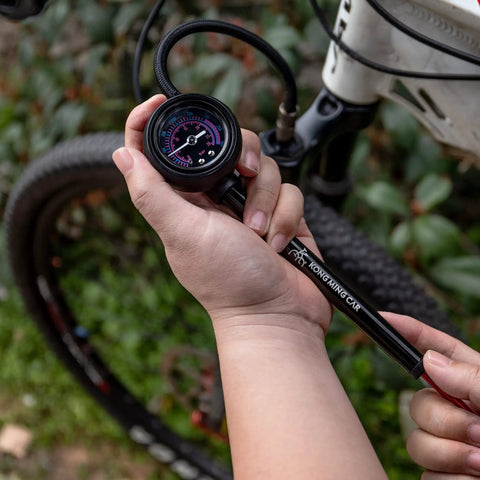 Person using high pressure bike shock pump with no loss Schrader valve for front fork and rear suspension 400 PSI gauge.