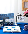 114 Piece Aesthetic Scrapbook Kit For DIY Junk Journaling Supplies including posters, stickers, and washi tape on a blue table.