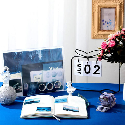 114 Piece Aesthetic Scrapbook Kit For DIY Junk Journaling Supplies including posters, stickers, and washi tape on a blue table.