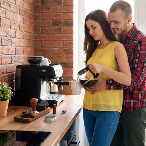 Couple using Pro Game Changer 7 Piece Espresso Essentials featuring 53 Mm Tamper for coffee preparation at home.
