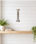 Raw 20 Gauge Mild Steel Column Cutout Wall Art for Craft and Garden Decor shown on white wall above shelf with plants.
