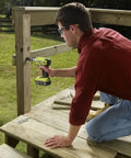 Person using Eighteen Volt Cordless Hammer Drill And Impact Driver Combo Kit for wood deck construction, black and green tools