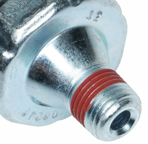 Close-up of premium engine oil pressure sender with light aftermarket replacement, showing metal build and red seal.