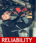 Side view of automotive technician under a lifted vehicle installing sway bar stabilizer link kit, red gloves visible