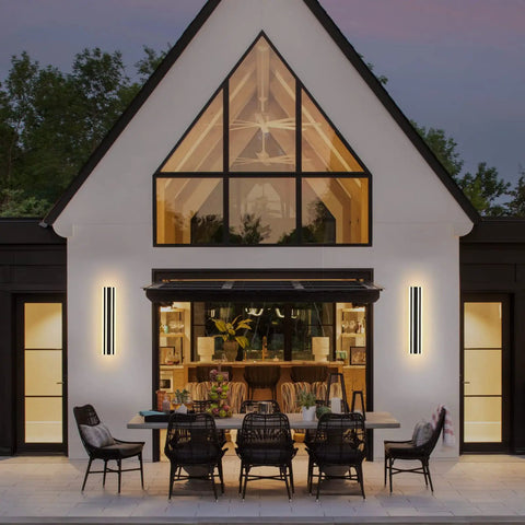 Evening view of a house exterior with 23.6 Inch Modern Outdoor Wall Sconce With 12W LED Black Exterior Light Fixture Frosted White Acrylic Porch Patio Waterproof IP65 For Garage Front Door Garden Tough As Nails illuminating a patio dining area.