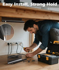 Man installing Under Desk Cable Management Tray Kit 26 Piece With Ventilated Hexagonal Design Includes Cable Clips Wire Ties Cord Holder And Screws For Office And Home Keeps Your Setup Neat Black under a wooden desk.