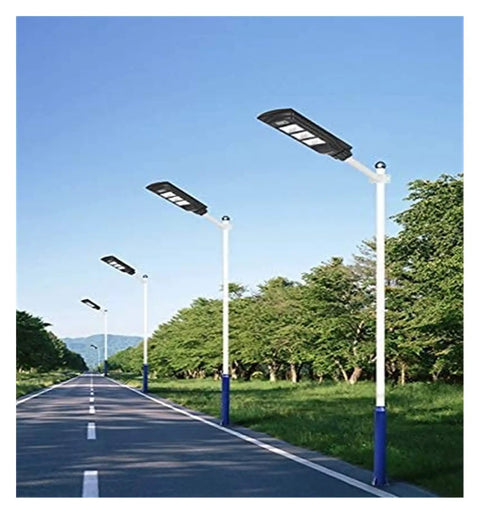 Badass Heavy Duty 350W Solar Floodlight With Photocensor And Motion Sensor Waterproof IP67 Outdoor Yard Security Lighting For Driveway Garden And Patio Hella Bright on a road with trees.