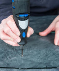 Front view of a black and blue cordless drill fitted with a 6mm diamond core tile bit drilling into dark stone