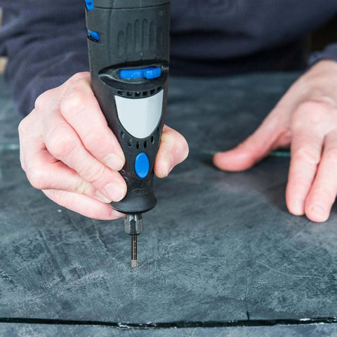 Front view of a black and blue cordless drill fitted with a 6mm diamond core tile bit drilling into dark stone