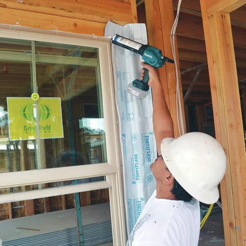 Worker using XGC01Z Cordless 18V Caulk And Adhesive Gun With Beefy 1100 Lbs Dispensing Power for window sealing on construction site.